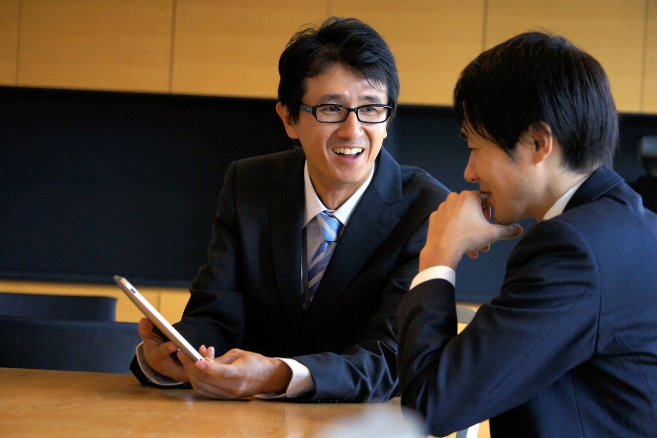 企業トラブルの話をする男性二人の写真
